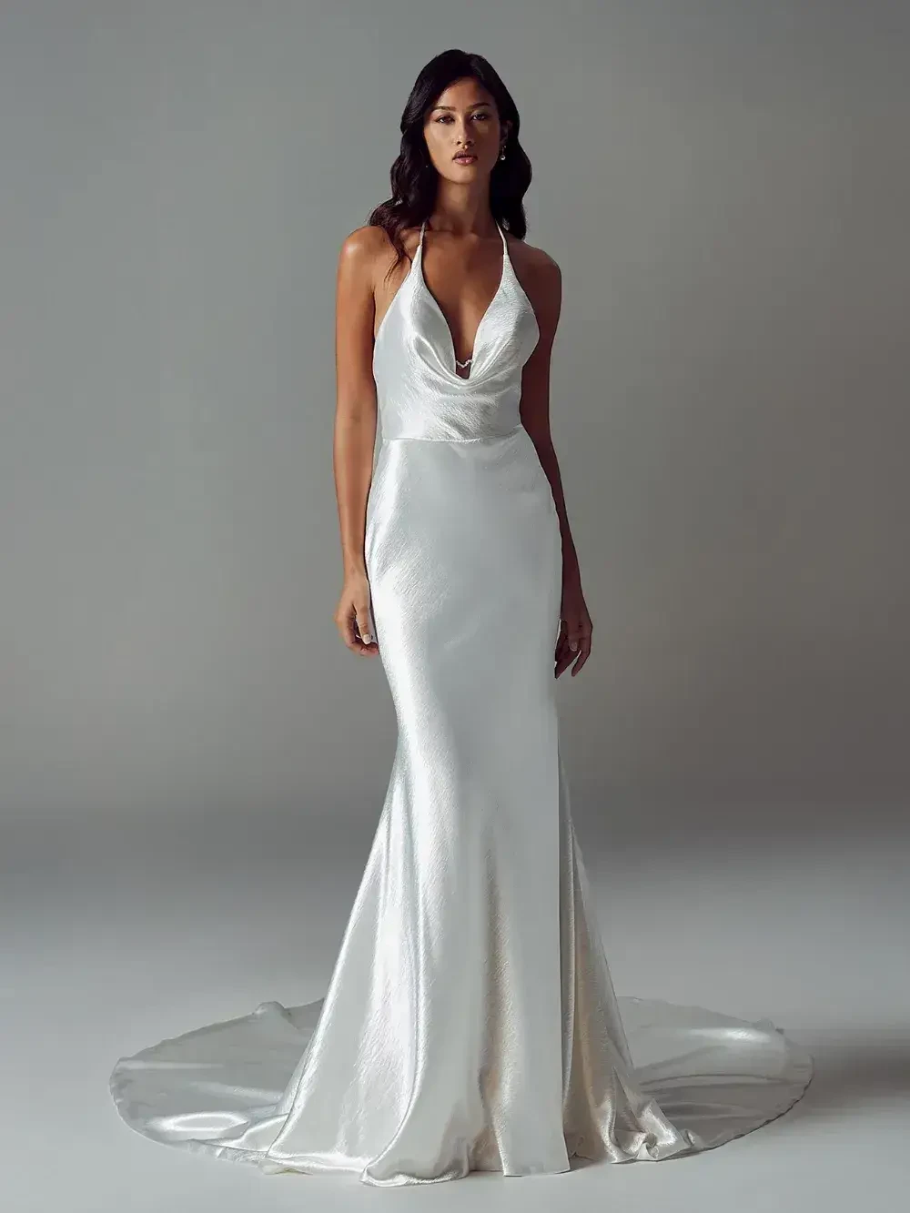 model is wearing a sleeveless bridal gown with a cowl neckline